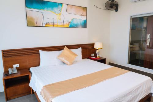 a bedroom with a large bed and a painting on the wall at WILD HORSE Hotel - Khách sạn biển Hải Tiến in Mỹ Ðuc