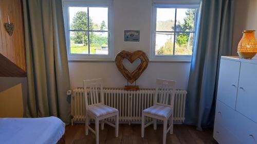 a bedroom with two chairs and a heart on the wall at Chalet Flandesbach in Velbert