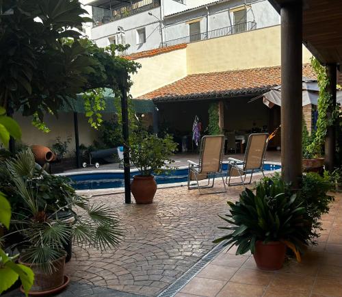 a patio with chairs and a pool with plants at CR Hanami House Boutique in Navaconcejo