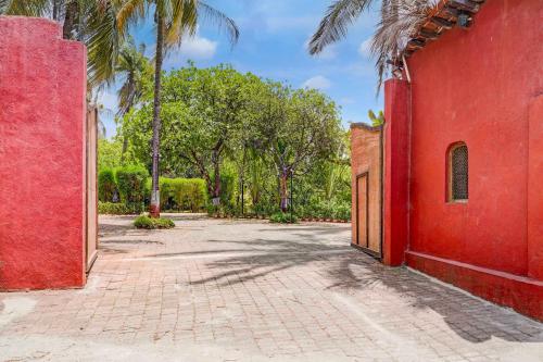 an empty courtyard with a red building and palm trees at Townhouse Palghar in Talāsri