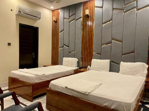 una habitación con dos camas y una silla en Karachi Guest House Gulshan-e-Iqbal, en Karachi