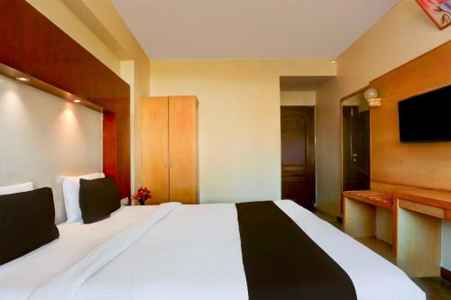 a bedroom with a large white bed with a flat screen tv at Townhouse Oak Udaipur City Railway Junction in Udaipur