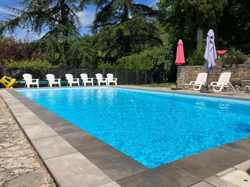 une piscine avec des chaises blanches et des parasols dans l'établissement A L Ombre du Tilleul, à Tour-de-Faure