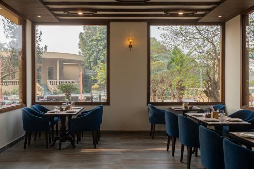 a restaurant with tables and chairs and large windows at Ametsa in Amritsar