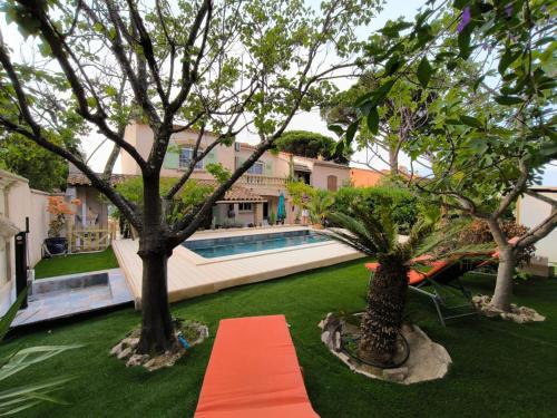 un chemin orange dans une cour avec des arbres et une piscine dans l'établissement Villa Domaine Font Mourier, à Cogolin