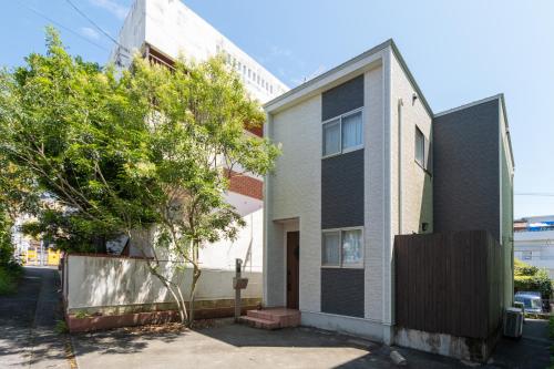 a white and black house with a tree next to it at キューブコザ in Okinawa City