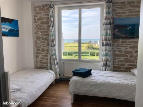 une chambre avec deux lits et une grande fenêtre dans l'établissement Soul Surfing Camp, à Plozévet