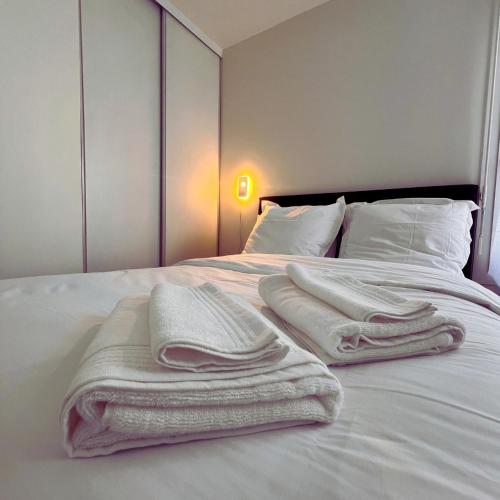- un lit avec des serviettes blanches assises au-dessus dans l'établissement Les Agnettes - Paris Metro - Wifi - Parking - Tout équipé, à Asnières-sur-Seine