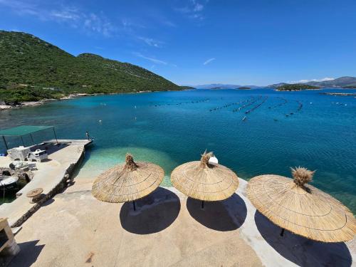a group of straw umbrellas sitting on a beach at Apartments Marinko in Janjina