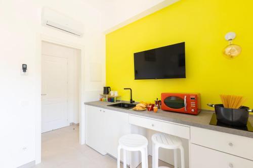a kitchen with a counter with a tv on a yellow wall at Orange y Lemon in Sant'Agnello