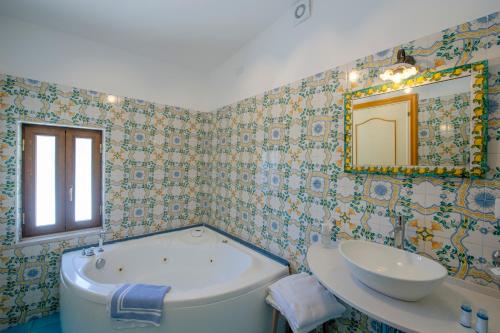 a bathroom with a tub and a sink and a mirror at Hotel Costa Diva in Praiano