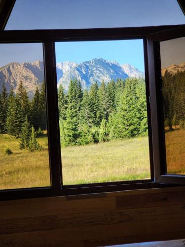 a window with a view of a field and mountains at Etno SELO Uskoci in Uskoci