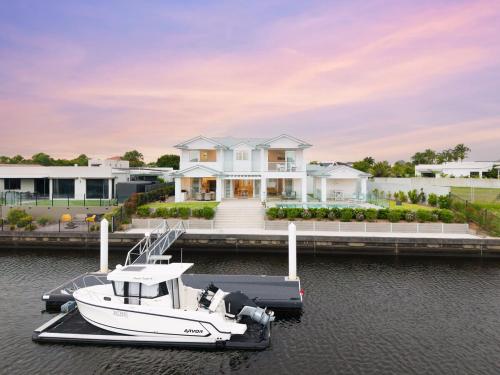 a house with a boat docked at a dock at Hamptons On Dux Retreat in Banksia Beach