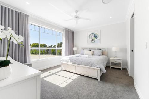 a white bedroom with a bed and a window at Hamptons On Dux Retreat in Banksia Beach
