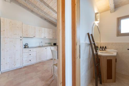 eine Küche mit weißen Schränken und einem Tisch in der Unterkunft Menhir Boutique Apartments- Adult Only- by Obiettivo vacanza Budoni in Tanaunella