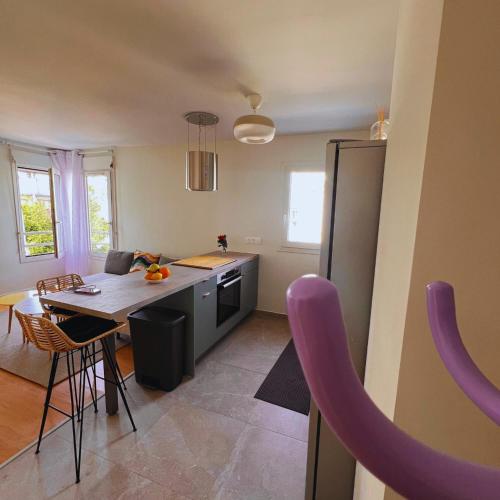 Il comprend une cuisine équipée d'une table et d'un réfrigérateur violet. dans l'établissement Les Agnettes - Paris Metro - Wifi - Parking - Tout équipé, à Asnières-sur-Seine