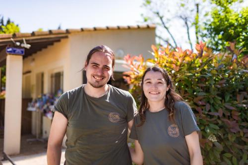 un homme et une femme debout devant une maison dans l'établissement Camping Porte des Alpilles by M.A DESTINATION GLAMPING, à Saint-Étienne-du-Grès