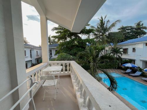 a balcony with a table and chairs next to a swimming pool at Rainforest - Casa Azure 5 Min walk to the beach in Calangute