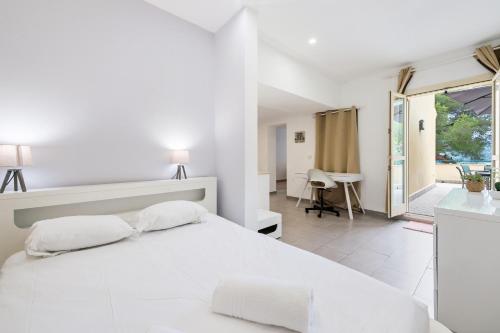 une chambre blanche avec un grand lit et un balcon dans l'établissement Charmante maison - Proche Monaco - Piscine partagée - DP, à Beausoleil