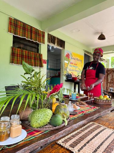 a woman standing in a kitchen with fruits and vegetables at Hibiscus Valley Inn in Marigot