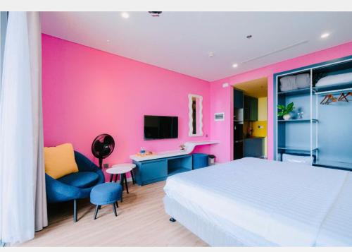 a bedroom with a white bed and a pink wall at FLAMINGO Ibiza HaiTien - Ivy Abtel in Thanh Hóa