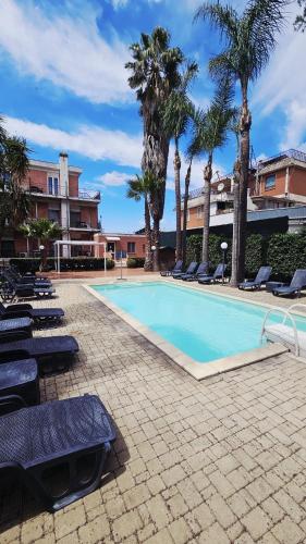 a large swimming pool with lounge chairs and palm trees at Hotel Giardino d'Europa in Rome