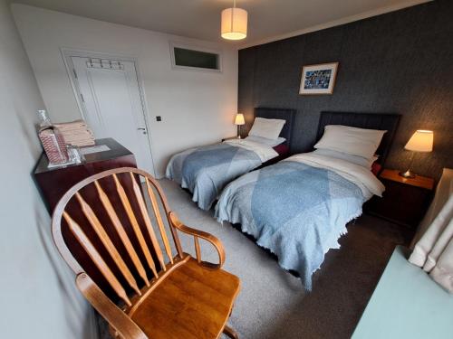 a bedroom with two beds and a chair and a chair at Westways House in Cobh