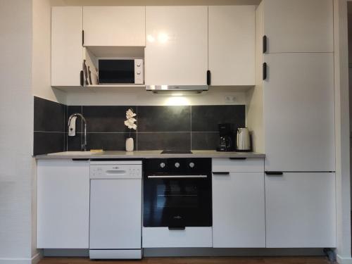 une cuisine avec des armoires blanches et un four noir dans l'établissement TOK TOK S6 Appartement 3Ch Moderne Plein Centre Seclin, à Seclin