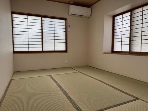 an empty room with two windows and a rug at 千田民宿 in Takayama