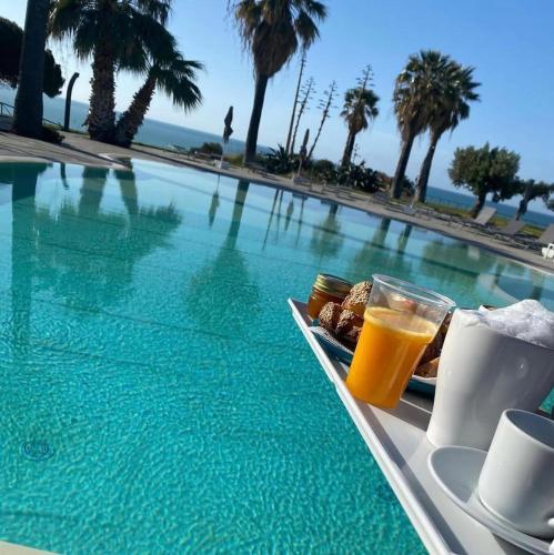 un vassoio di cibo e succo d'arancia accanto a una piscina di Bellavista a Realmonte