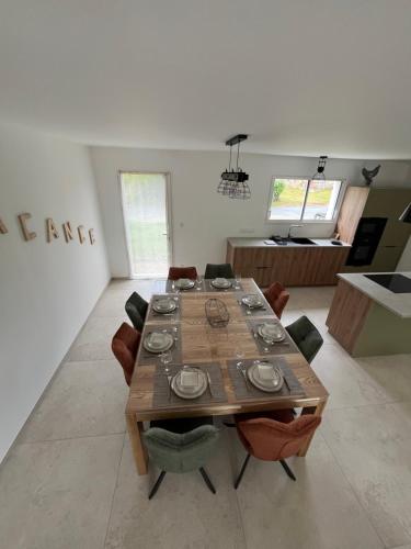 une salle à manger avec une table et des chaises en bois dans l'établissement Maison neuve tout confort avec jardin, à Le Bourdet