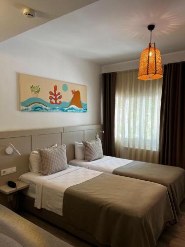 a hotel room with two beds and a chandelier at Hotel Gumusluk in Gümüşlük