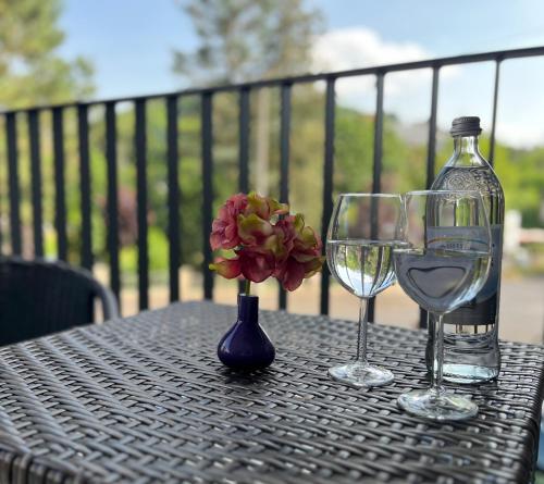 a table with two wine glasses and a flower in a vase at Sanssouci-FeWo 09 in Bad Kissingen