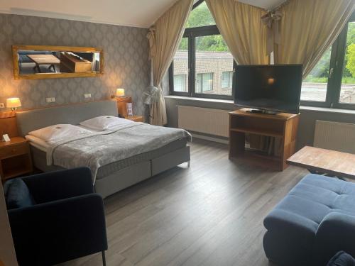 a bedroom with a bed and a tv and a couch at Burg Wegberg Hotel & Eventlocation in Wegberg
