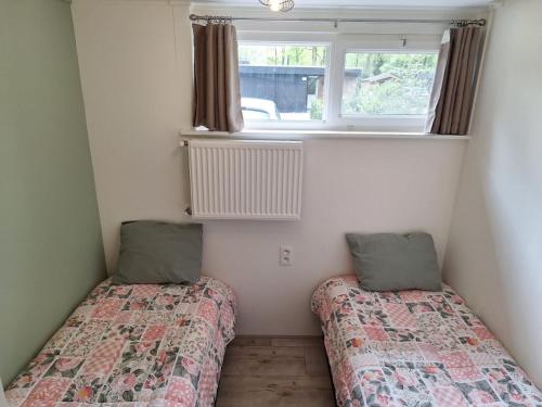 two beds in a small room with a window at Vrijstaande vakantiebungalow met optimale privacy!! in Rekem