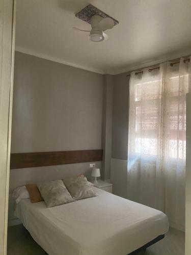 a bedroom with a white bed and a window at Apto con patio y barbacoa BBQ H de la Reina in Córdoba