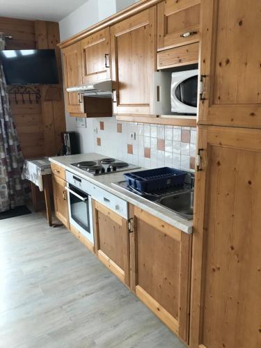 une cuisine avec des armoires en bois et un four à plaques de cuisson dans l'établissement Montana 2, à Pralognan-la-Vanoise