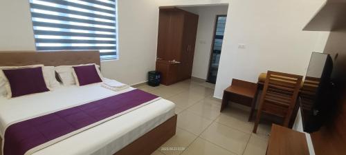 a bedroom with a bed and a desk and a television at Cardamom Vista Homestay in Thekkady