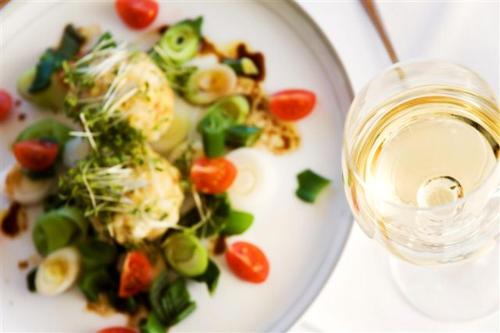 a plate of food with vegetables and a glass of wine at Hotel Wieslhof in Collepietra