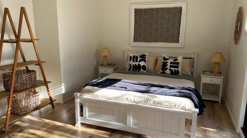 a bedroom with a bed with pillows and a ladder at Coastal Drift - Iluka -Apartment 2 - No Pets Allowed in Iluka