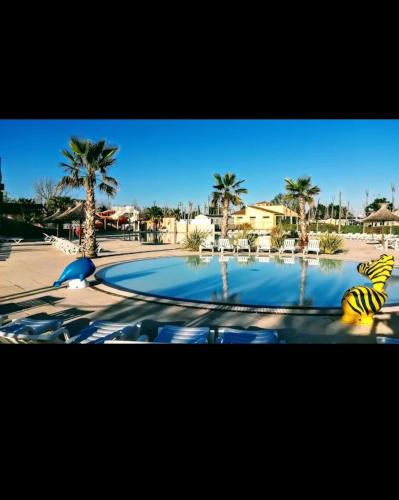 une piscine avec une statue de tigre dans un complexe hôtelier dans l'établissement Mobil Home dans Camping 4 étoiles, à Valras-Plage
