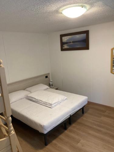 a small bedroom with a bed with white sheets at casa Veronica in Pieve Di Ledro