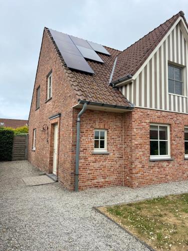 a brick house with solar panels on the roof at Key Corner, Holiday home in De Haan