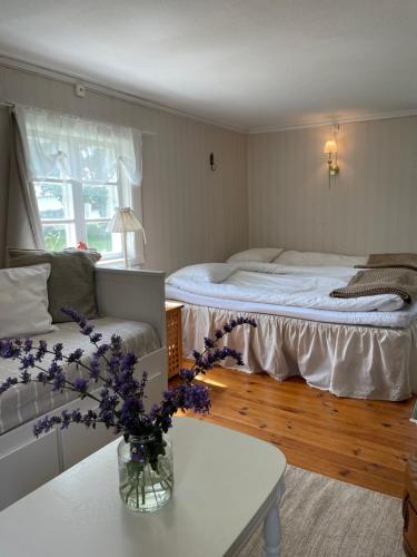 a bedroom with a bed and a vase of flowers on a table at Trevligt eget hus med kakelugn i lantlig miljö in Vikingstad