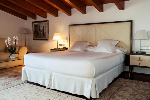 a bedroom with a large white bed with a large headboard at Mirador de Dalt Vila-Relais & Chateaux in Ibiza Town