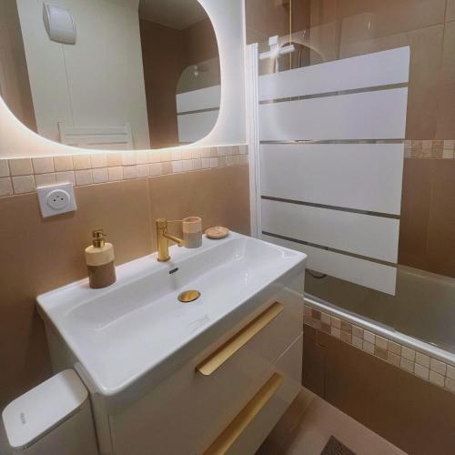 une salle de bain avec un lavabo blanc et un miroir dans l'établissement Les Agnettes - Paris Metro - Wifi - Parking - Tout équipé, à Asnières-sur-Seine