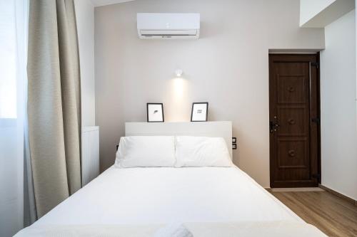 a bedroom with a white bed with two pictures on the wall at Verdant Haven - 5 Min from the Sea in Zipárion