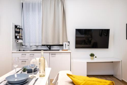 a white kitchen with a dining table and a tv at Verdant Haven - 5 Min from the Sea in Zipárion