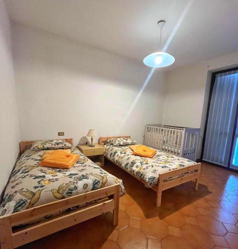 two twin beds in a room with a window at LA PANORAMICA Svegliati con la Vista delle Alpi dalle Camere e Terrazza Ampia in Berzo