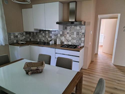 a kitchen with white cabinets and a table with chairs at La casa di Memy in Gualdo Tadino